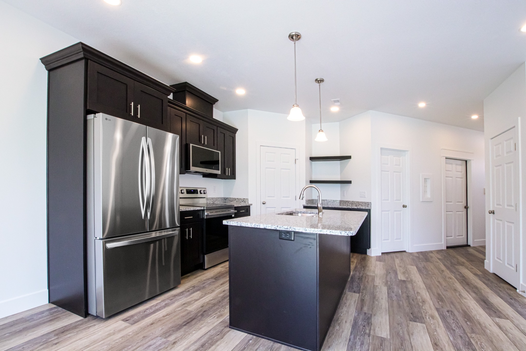 Custom home kitchen with dark cabinetry and stainless steel appliances